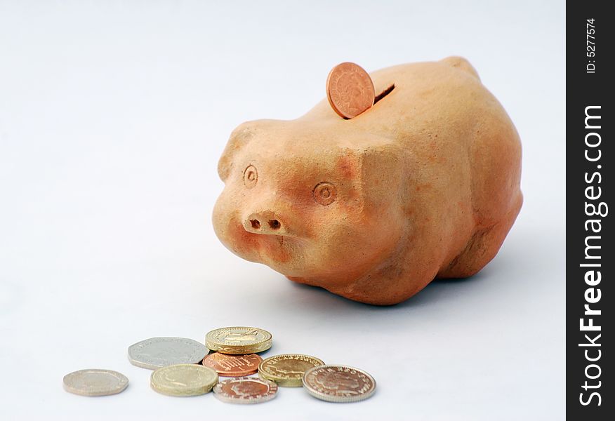 British coins and piggy bank over white. British coins and piggy bank over white