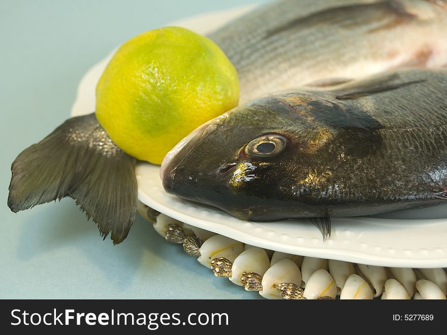 Tow raw fishes with half lemon. Tow raw fishes with half lemon