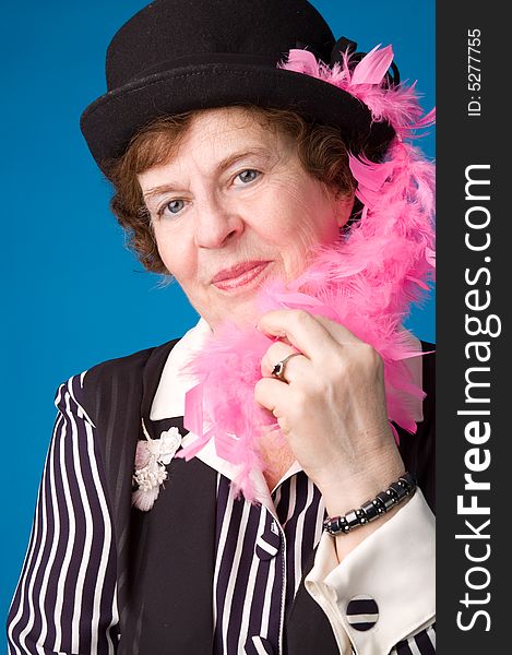 The cheerful elderly woman in black hat on a blue background. The cheerful elderly woman in black hat on a blue background.