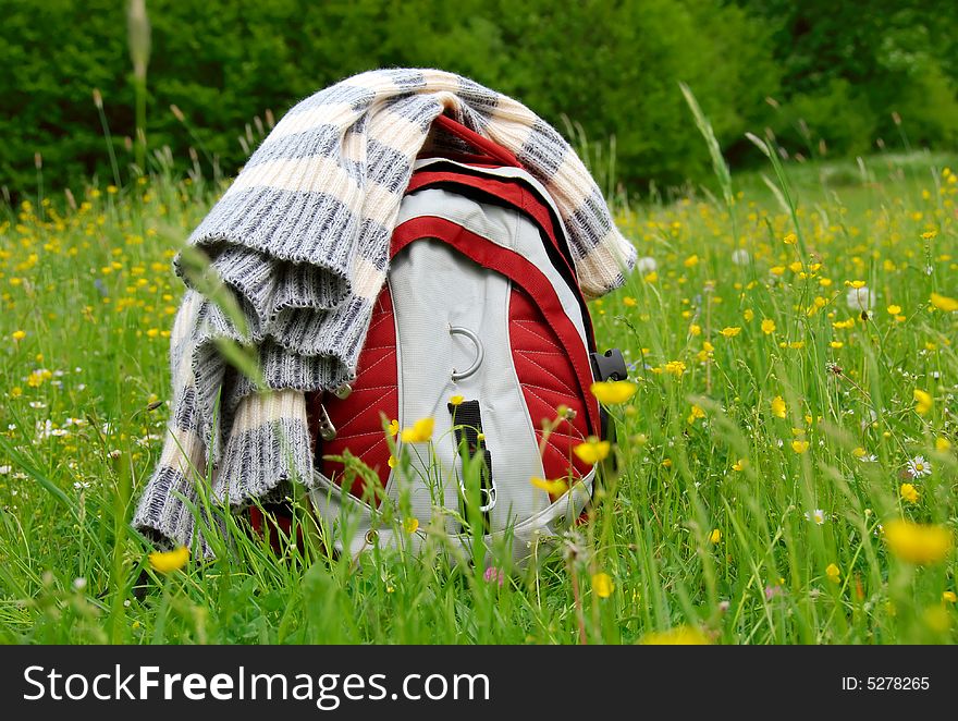 Red backpack and sweater in belts lie on the grass