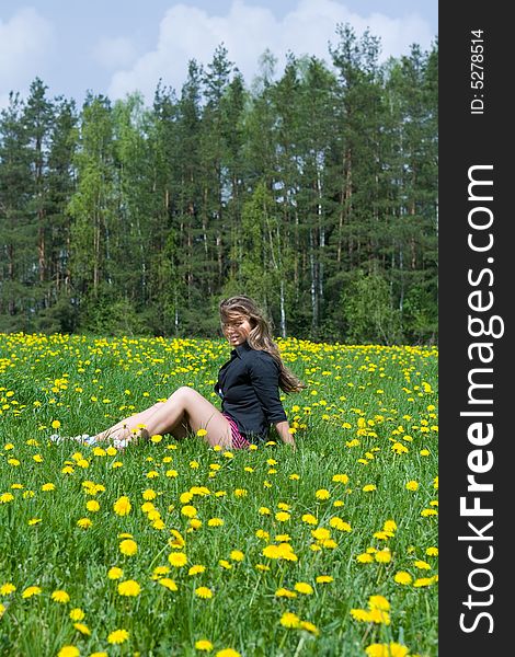 Young girl in short skirt on dandelion field