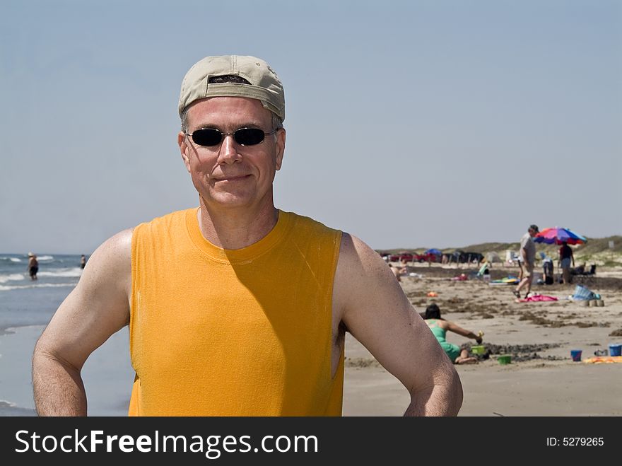 A smiling man at the beach wearing sunglasses and his baseball hat on backwards. A smiling man at the beach wearing sunglasses and his baseball hat on backwards.