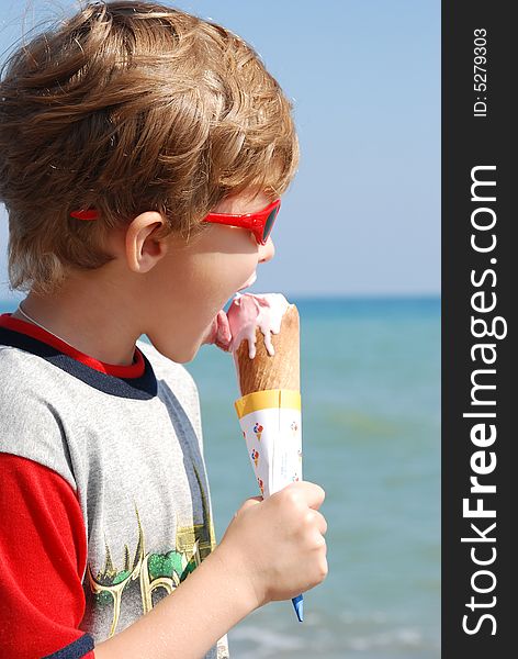 On seacoast the boy eats ice-cream