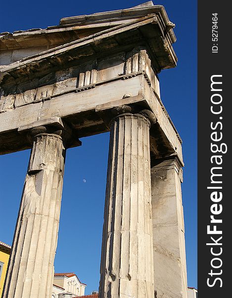 Column ruins in Athens monastiraki. Moon is visible between them. Column ruins in Athens monastiraki. Moon is visible between them