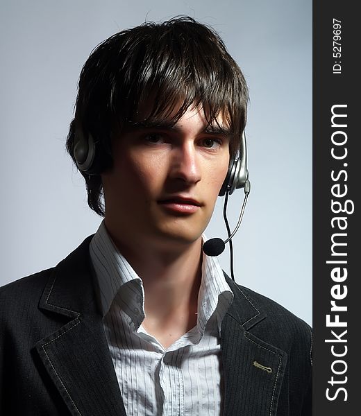 A portrait about an attractive call center operator man who is smiling and he has a headphone. He is wearing a white shirt and a black suit. A portrait about an attractive call center operator man who is smiling and he has a headphone. He is wearing a white shirt and a black suit.