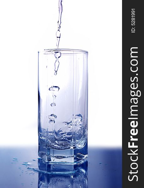 Big long drop of cold water poured into empty glass (isolated on white background). Big long drop of cold water poured into empty glass (isolated on white background)