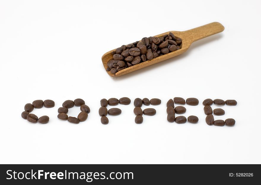 Studio shot of scoop of coffee beans with the word coffee spelled out in beans.