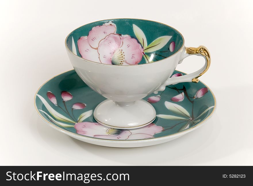 An antique tea cup with gold detail and floral pattern. An antique tea cup with gold detail and floral pattern