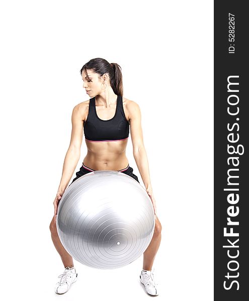 Beautiful brunette woman exercising with a gray yoga ball