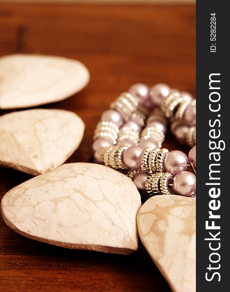 Wooden hearts lying on a wood table surrounding a bracelet. Wooden hearts lying on a wood table surrounding a bracelet