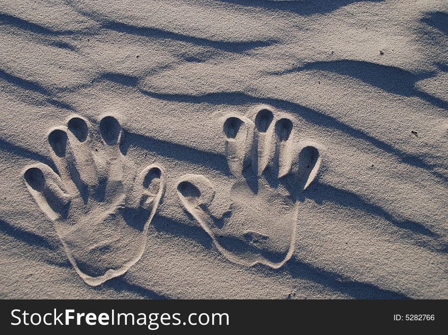 Two child's hand stamp on the sand