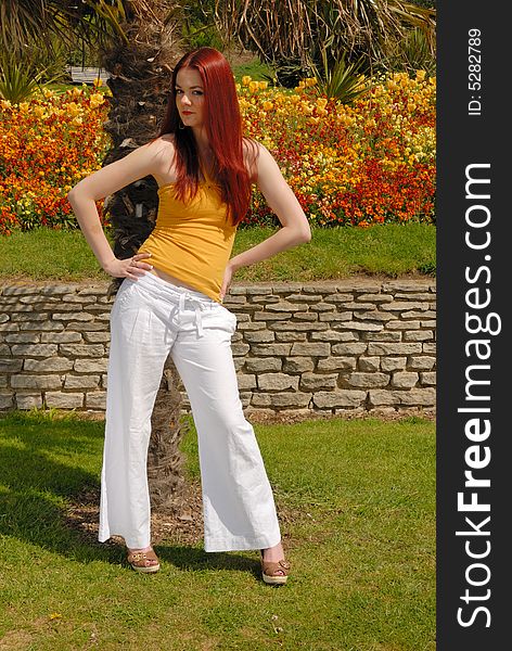 Cute girl  in yellow top and white pants in beautiful gardens. Cute girl  in yellow top and white pants in beautiful gardens