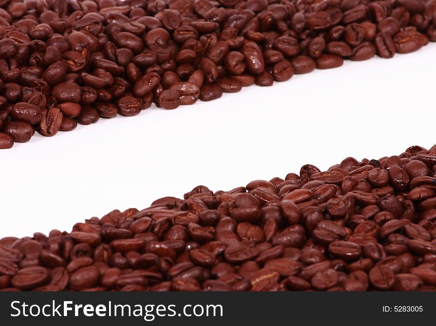 Two diagonal piles of coffee beans on a white background. Two diagonal piles of coffee beans on a white background.