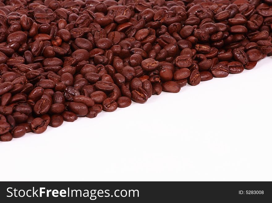 A diagonal pile of coffee beans on a white background. A diagonal pile of coffee beans on a white background.