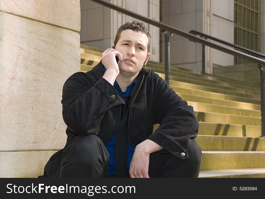 Business guy sitting on the steps outside of a building. Business guy sitting on the steps outside of a building.