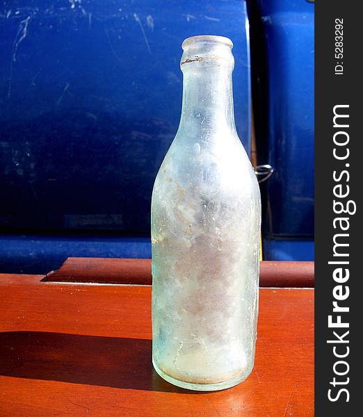 Frosted glass bottle sitting on a wooden shelf