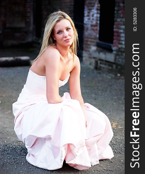 Attractive blond woman kneeling down in a bridesmaid's dress. Vertically framed shot. Attractive blond woman kneeling down in a bridesmaid's dress. Vertically framed shot.