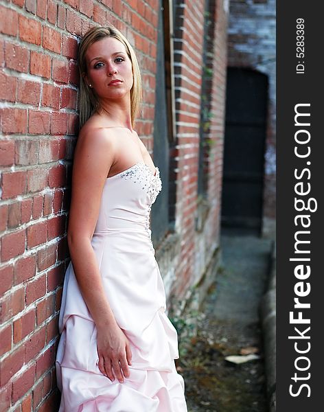 Outdoor shot of a attrative bridesmaid leaning against a red brick building. Outdoor shot of a attrative bridesmaid leaning against a red brick building.