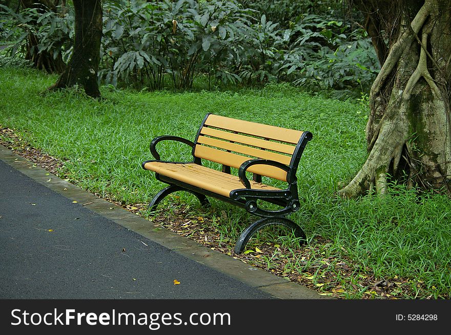 A yellow chair by road side in the park.