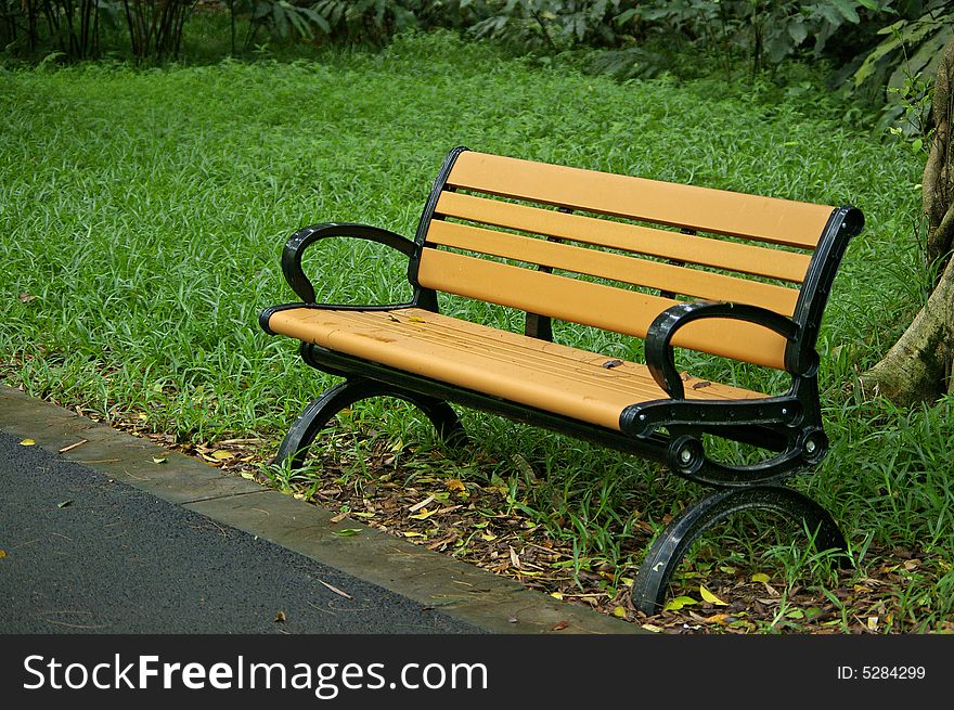 A yellow chair by road side in the park.