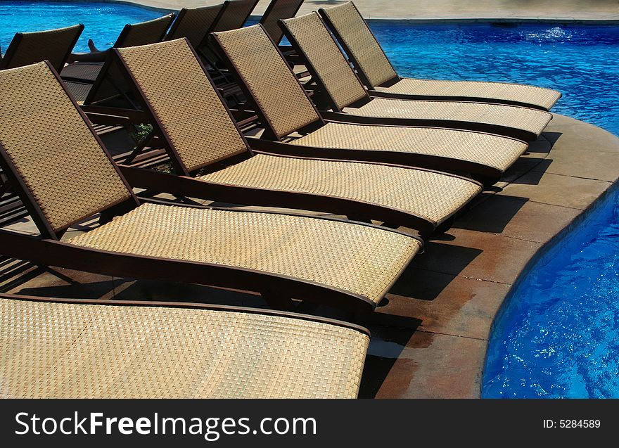 Lounge chairs besides a swimming pool. Lounge chairs besides a swimming pool