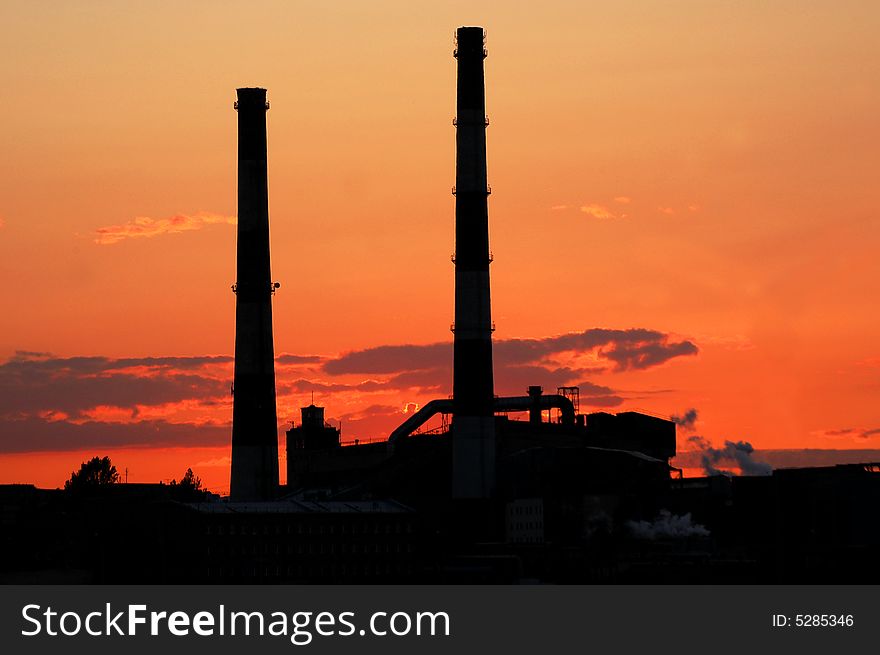 A factory with two smoke-stacks at red light. A factory with two smoke-stacks at red light