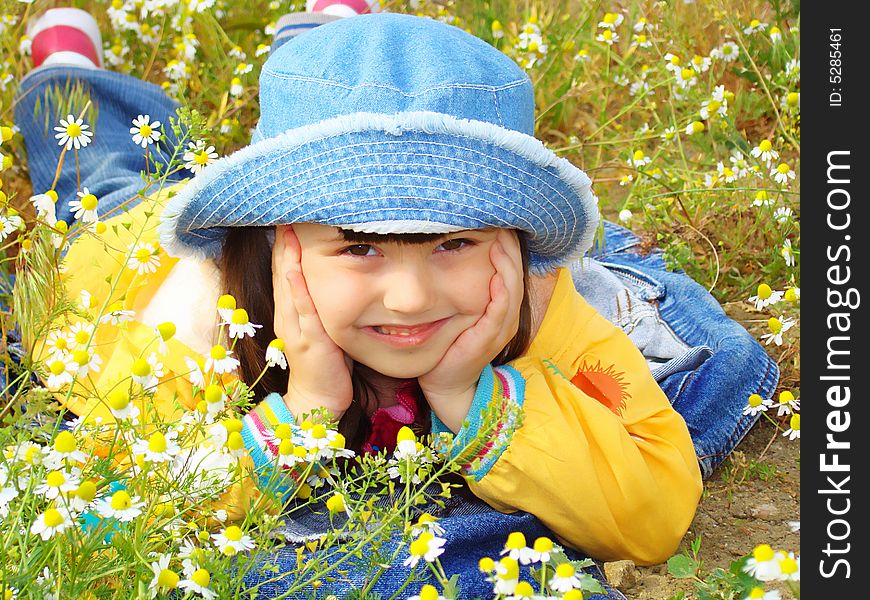 Girl with brown eyes rests on the chamomile field. Little coquette with a hat. Girl with brown eyes rests on the chamomile field. Little coquette with a hat.