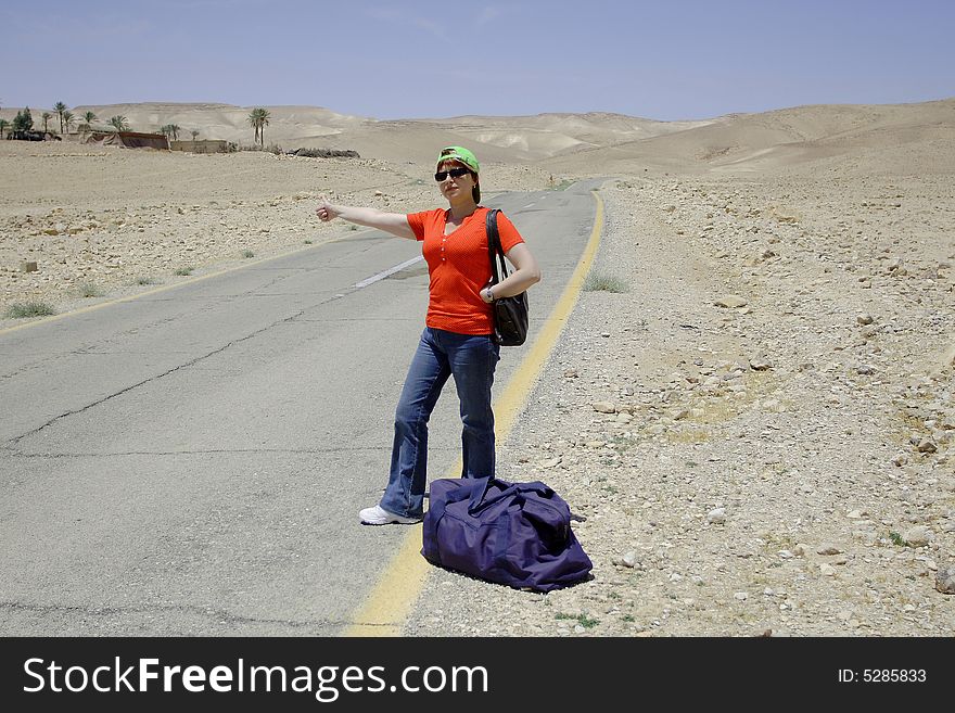 A young female hitch-hiker with her luggage. A young female hitch-hiker with her luggage