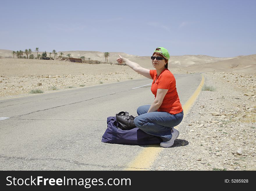 A young female hitch-hiker with her luggage. A young female hitch-hiker with her luggage