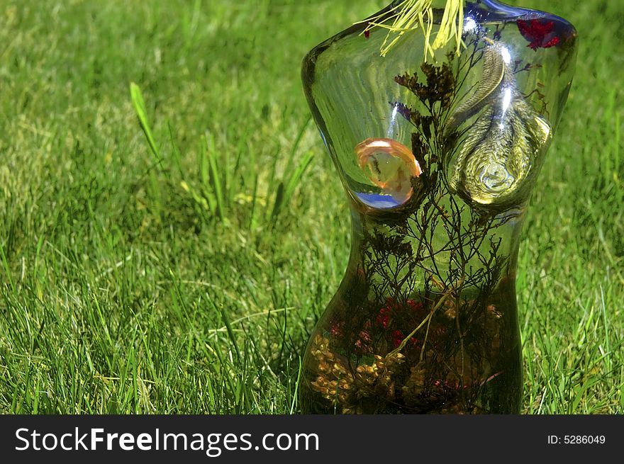 Glass woman with flowers on a background of green grass. Glass woman with flowers on a background of green grass