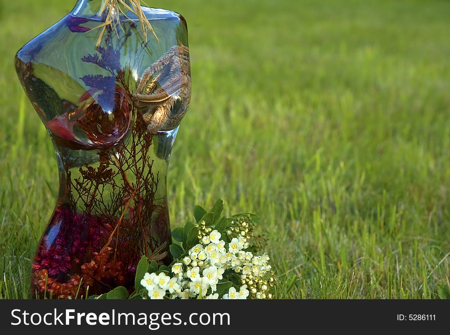 Glass woman with flowers on a background of green grass. Glass woman with flowers on a background of green grass