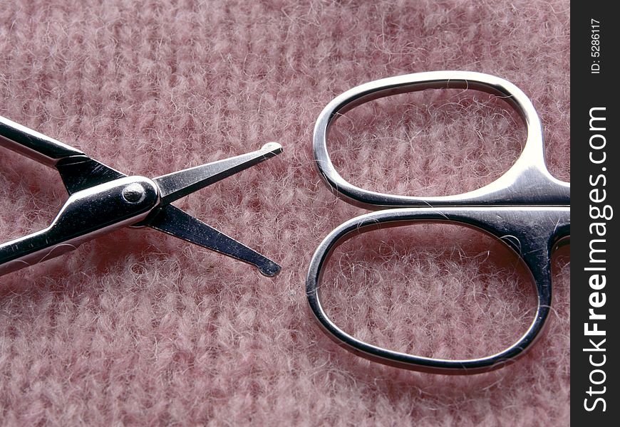 Two pair of scissors on textured pink background.  Half of each pair of scissors are in the image.  The pink background is a soft textile with a knit pattern.