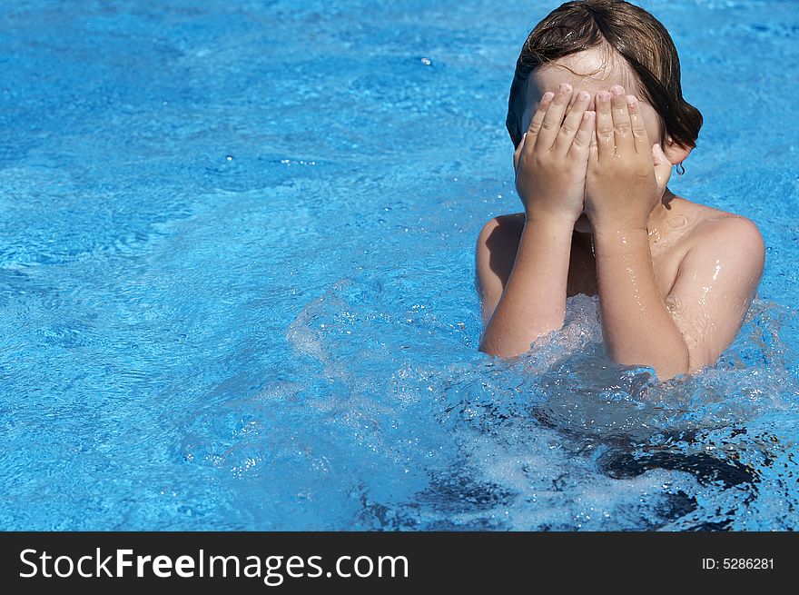 A boy playing in a pool of water during the summer. A boy playing in a pool of water during the summer