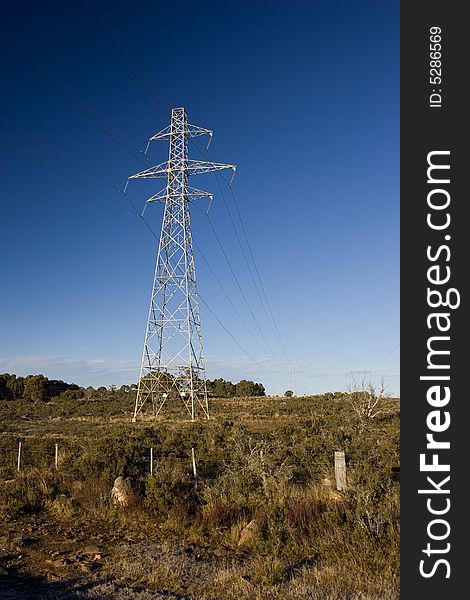 Power pylons crossing farmland with blue sky