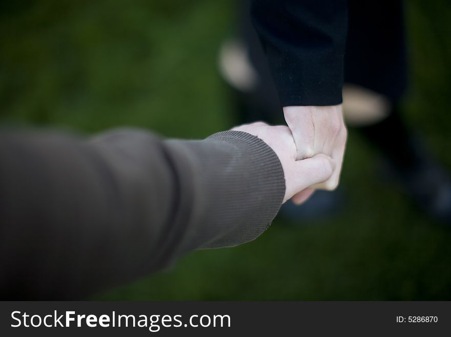 Close up of hands of man and woman with green grass background. Close up of hands of man and woman with green grass background