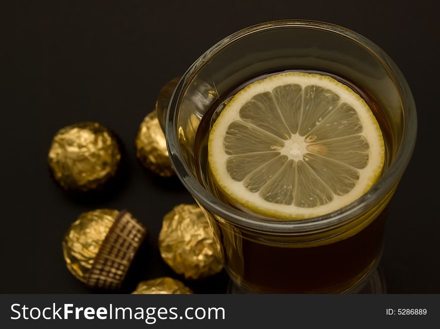 Tea with a lemon in glass chake and candies