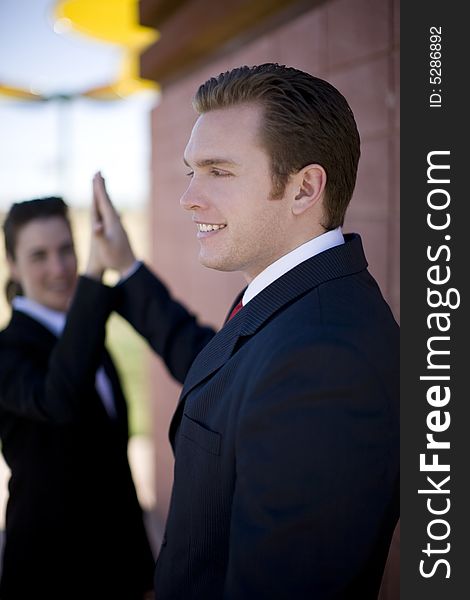 Businessman and businesswoman in suits smiling giving high-five. Businessman and businesswoman in suits smiling giving high-five