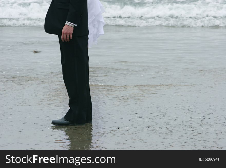 Bride and groom standing on beach with waves. Bride and groom standing on beach with waves