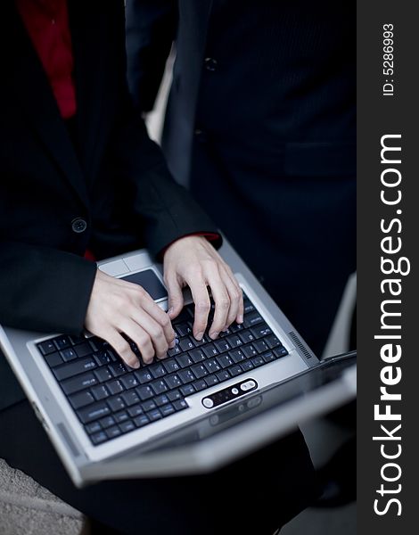 Businesswoman typing on laptop with businessman standing next to her. Businesswoman typing on laptop with businessman standing next to her