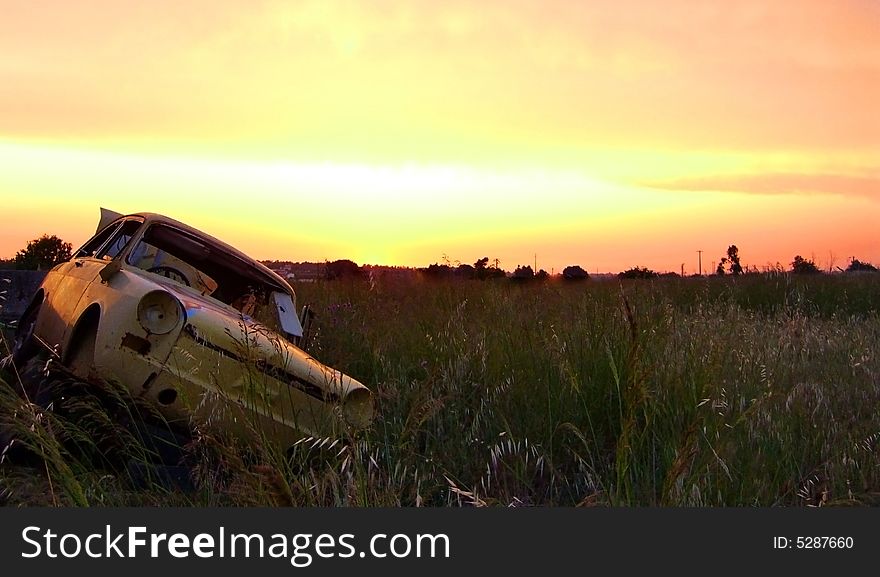 Abandoned rusted car on a grass field at sunset. Abandoned rusted car on a grass field at sunset.