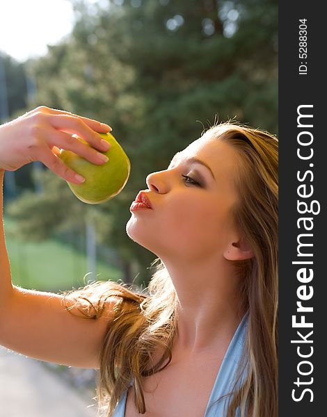 Girl with apple on sunset on green background