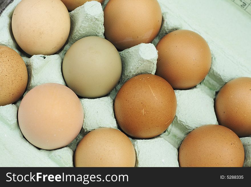 Fresh free-range chicken eggs of assorted sizes and colour in a green egg box