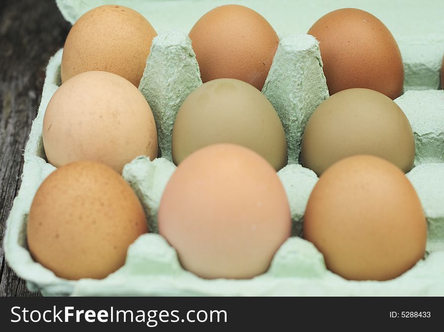 Fresh free-range chicken eggs of assorted sizes and colour in a green egg box