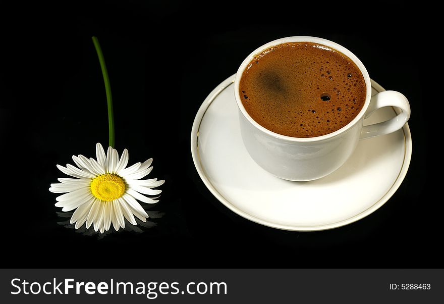 Beautiful camomile and cup of coffee on a black background. Beautiful camomile and cup of coffee on a black background