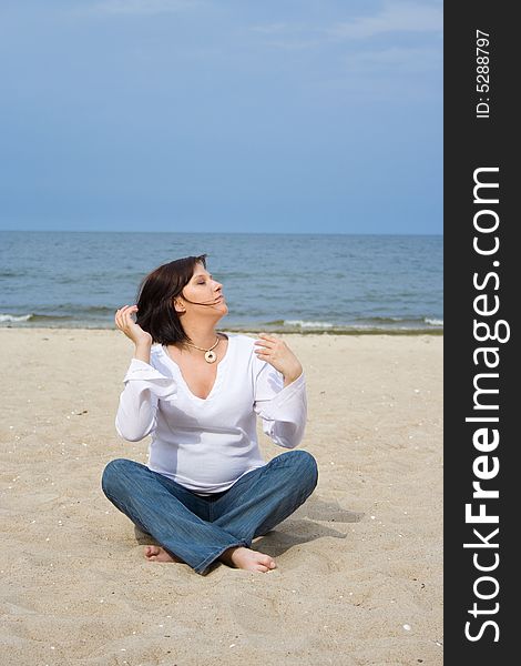 Pregnant woman sitting on the sand. Pregnant woman sitting on the sand