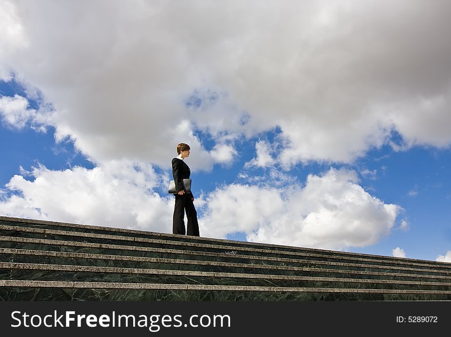 Businesswoman posing against huge cloudscape. Businesswoman posing against huge cloudscape.