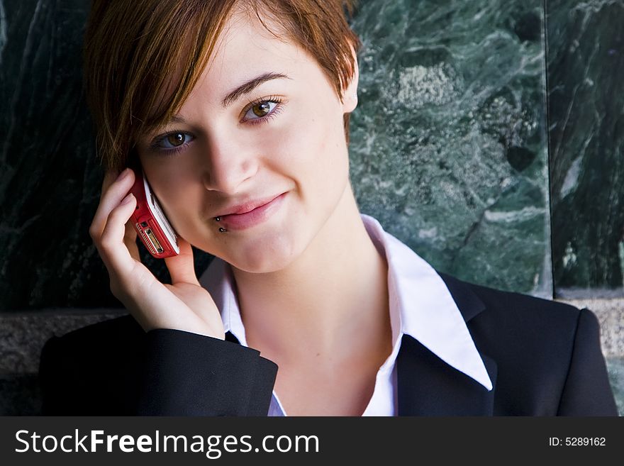 Beautiful businesswoman at phone over marble background.