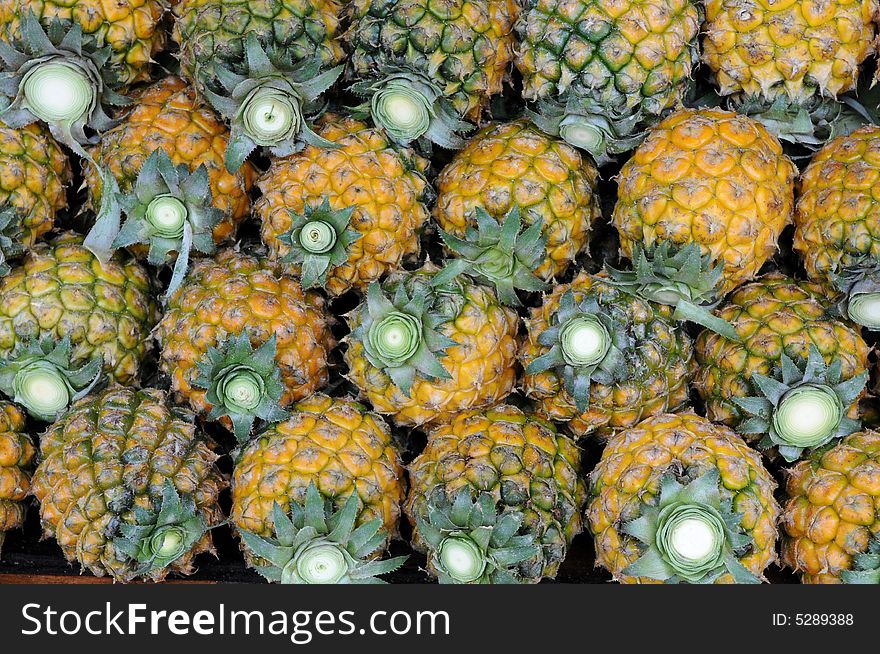 A pile of fresh fragrant and juicy golden pineapples. A pile of fresh fragrant and juicy golden pineapples.