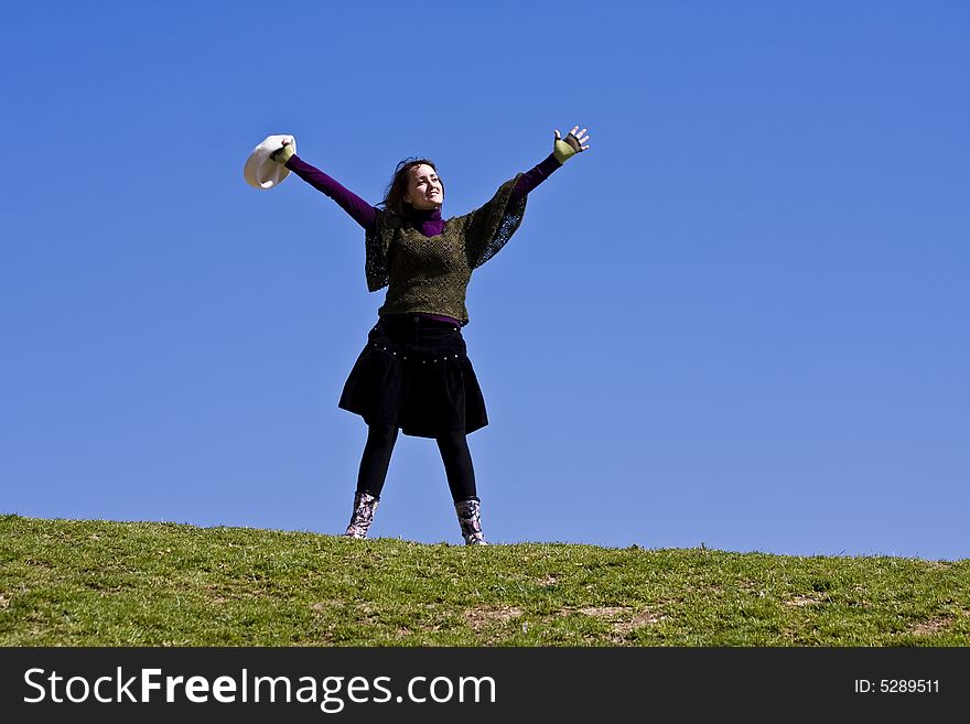 Happy girl with raised arms on the grass