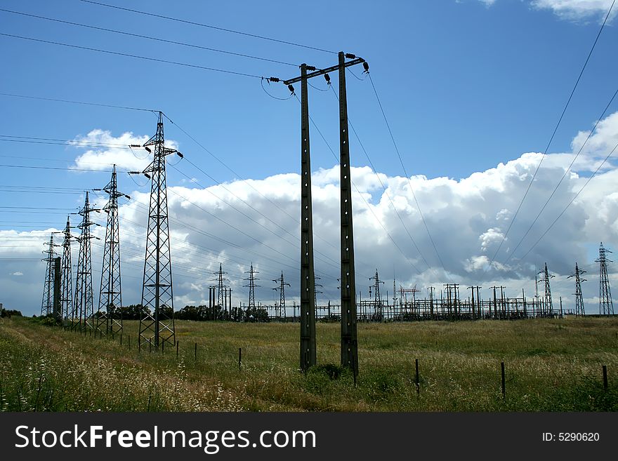 Electric power station in the field in blue cloudy sky. Electric power station in the field in blue cloudy sky